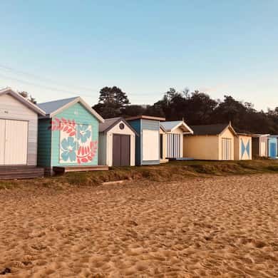 A row of painted bathing boxes on the sand of a bay beach