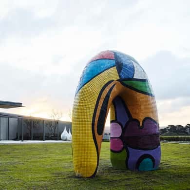 A large painted sculpture on a lawn above the sea at a winery