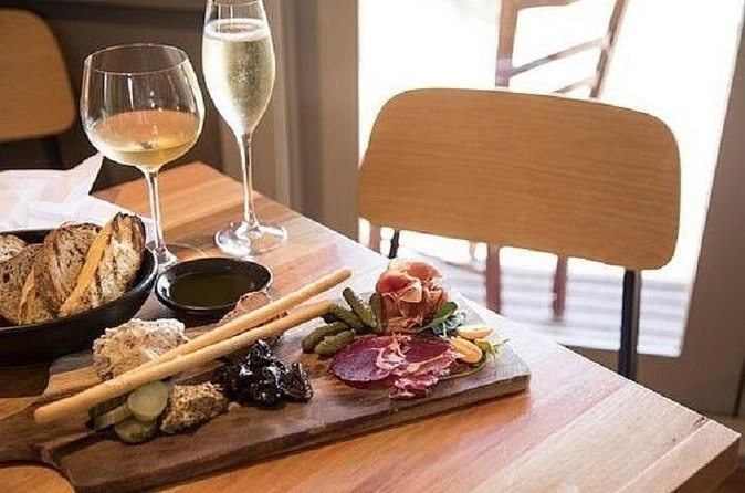 A glass of white, a glass of sparkling and a grazing board on a winery table
