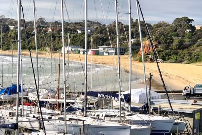 Yachts moored in a small marina on the bay, with the beach behind